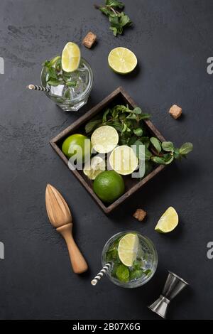 Mojito cocktail Ingrédients, chaux, menthe, eau, jigger sur table noire. Vue de dessus. Format vertical. Banque D'Images