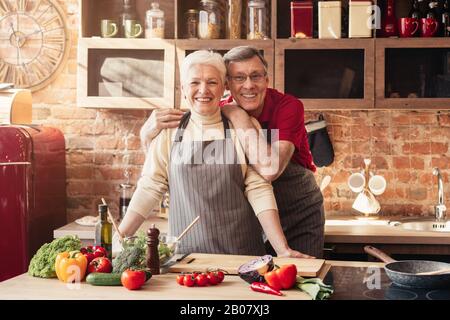 Couple de personnes âgées souriantes se posant ensemble dans l'intérieur de la cuisine Banque D'Images