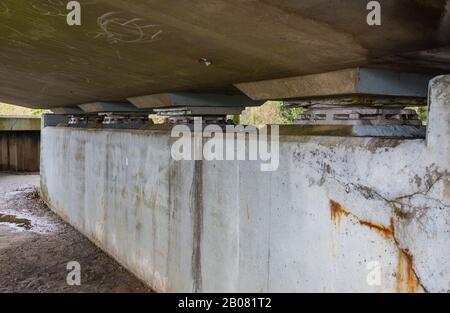 Soutenez les roulements sur un pont routier en béton, montrant probablement des fissures de contrainte dans le béton. Patins de support de roulement de pont. Banque D'Images