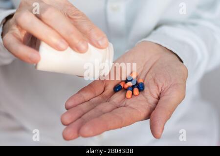 Close up main de femme tenant une médecine, vieille femme avec les mains sur la pilule pilules déversant en bouteille Banque D'Images