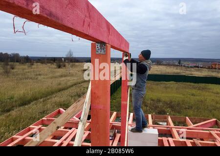 Rafters bois contre le ciel bleu, le maître travaille sur l'installation de barres. Banque D'Images