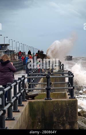 Les gens se rassemblent sur le front de mer pour regarder et prendre des photos de Storm Ciara comme des vagues crash au-dessus du mur de la mer à New Brighton Wallasey Royaume-Uni Banque D'Images