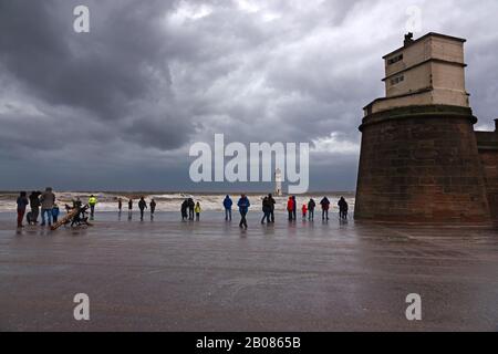 Les gens se réunissent sur le front de mer pour regarder et prendre des photos de Storm Ciara au phare de fort Perch Rock à New Brighton Wallasey Royaume-Uni Banque D'Images