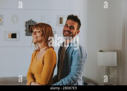 Les jeunes couples passent du temps ensemble à la maison. L'homme et la femme dansent dans le salon et s'amusent. Banque D'Images