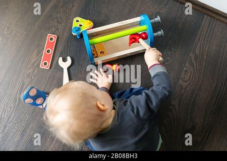 enfant jouant avec un coffret à outils en bois sur le sol à la maison Banque D'Images
