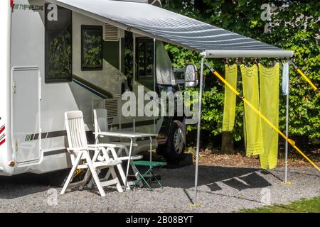 Trois serviettes vertes pendantes pour sécher dans le soleil chaud, du store / soleil ombragé d'une caravane, sur un camping sans personne autour. Engand, Royaume-Uni. Banque D'Images