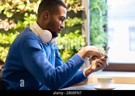 Portrait d'un gars noir écoutant de la musique au café Banque D'Images