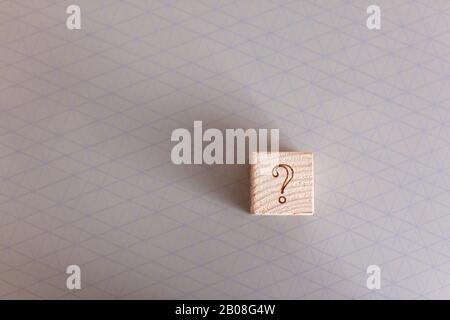 Point d'interrogation sur cube de jouet en bois texturé naturel sur table beige avec motif graphique, espace de copie. Vue latérale. Confusion, incertitude, suspense educati Banque D'Images