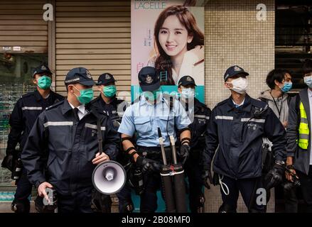 Les policiers anti-émeutes portent des masques comme mesure préventive à la suite de l'épidémie de Coronavirus pendant qu'ils sont en garde debout lors d'une manifestation contre l'utilisation d'un centre de quarantaine à Cheung Sha Wan à Hong Kong. Banque D'Images