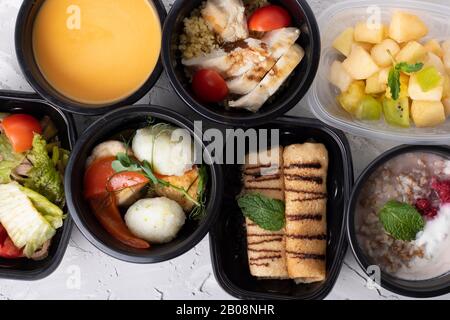 Repas préparé pour le petit-déjeuner, le déjeuner et le dîner dans des contenants noirs pour une journée complète comprenant des flocons d'avoine coupés en acier, une salade de poulet du sud-ouest et du bœuf corné A. Banque D'Images