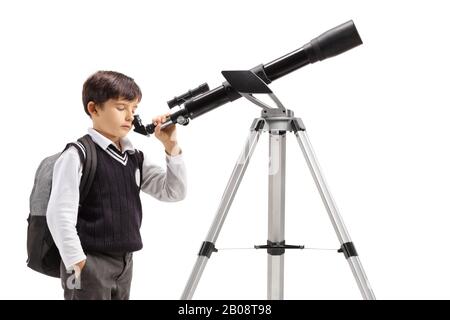 Garçon dans un uniforme d'école regardant par un télescope isolé sur fond blanc Banque D'Images