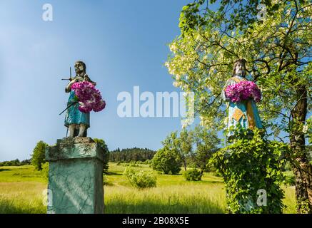 Statues religieuses, faux arbre d'acacia fleuris sur la route près du village de Berest, bas massif de Beskids, Carpates occidentales, Malopolska, Pologne Banque D'Images