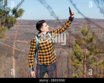 homme dans des vêtements décontractés perdu dans la nature essayer de prendre le signal sur le téléphone Banque D'Images