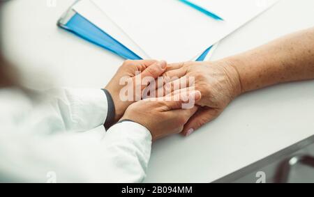Le médecin tient la main d'une femme âgée. Une infirmière prend en charge une patiente âgée. Banque D'Images