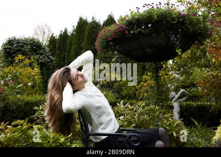 bel adolescent avec de longs cheveux, s'étirant dans le jardin formel Banque D'Images