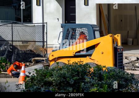 Niveler et niveler la machine, niveler le sol pour une nouvelle allée et un nouveau passage en face de la nouvelle construction. Banque D'Images