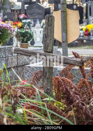 Une petite croix de bois sur une tombe oubliée dans un cimetière en Pologne Banque D'Images