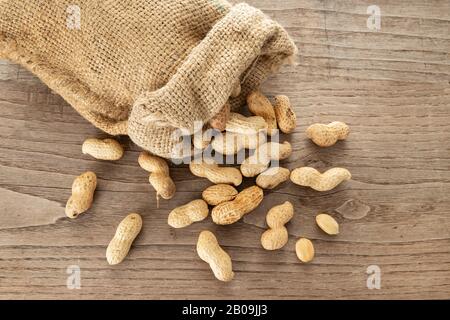 Sac à dos et arachides sur table en bois rustique. Arachis hypogaea Banque D'Images
