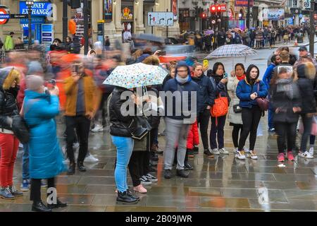 West End, Londres, Royaume-Uni. 19 février 2020. Les touristes sur Piccadilly Circus font le plus souvent le temps. Les touristes et les Londoniens font le maximum de courtes lacunes dans la pluie lors d'une journée humide mais douce dans le West End de Londres. Crédit: Imagetraceur/Alay Live News Banque D'Images