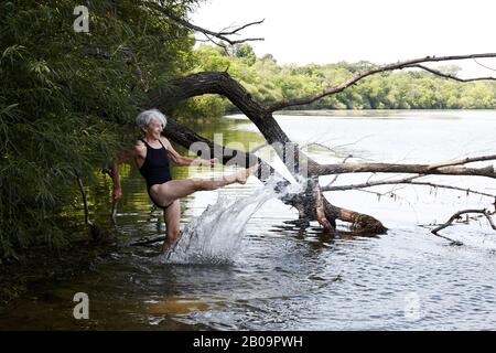 Femme senior portant un maillot de bain barbotant dans le lac Harriet. Banque D'Images