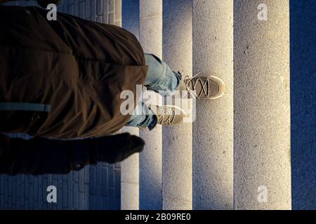 Jambes femelles dans des bottes d'hiver en daim, marchant sur les marches en pierre illuminées, la nuit. Vue de dessus Banque D'Images