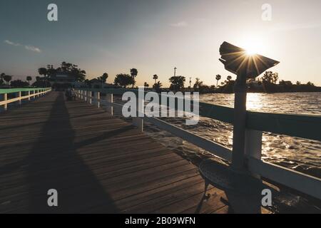 PINE ISLAND, FLORIDE - 17 JANVIER 2020. Sunburst derrière une jetée sur la jetée de Bokeelia au coucher du soleil. La femme lit en arrière-plan. Banque D'Images