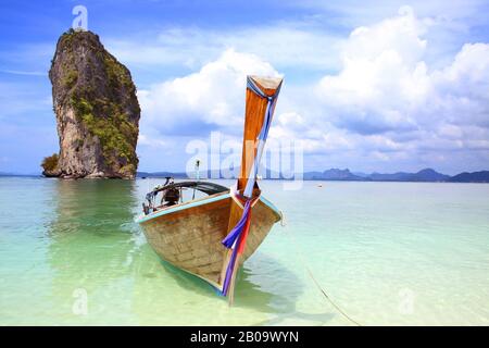 Un bateau de pêche thaïlandais attaché sur la plage avec une belle île en arrière-plan, Krabi, Thaïlande. Banque D'Images