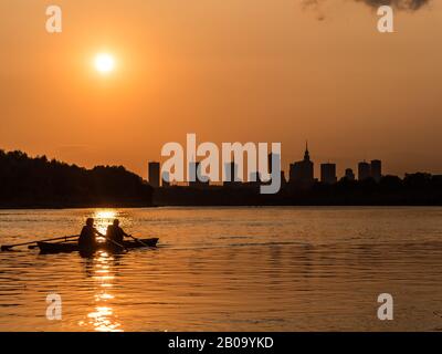 Panorama de Varsovie avec gratte-ciel dans le centre ville avec une belle réflexion du soleil à Wisła et des bateaux naviguant sur la rivière pendant le coucher du soleil Banque D'Images