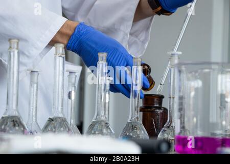 Scientifique faisant une expérience en gants bleus Banque D'Images