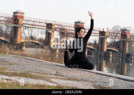 Portrait de la fille de sport faisant de l'exercice d'étirements de yoga sur le bord de la rivière Banque D'Images