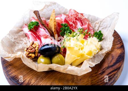 Ensemble de vins : cou sec, fromage, olives et crackers de seigle. Seth est allongé sur du papier parchemin froissé sur un plateau rond en bois Sur fond blanc. Banque D'Images