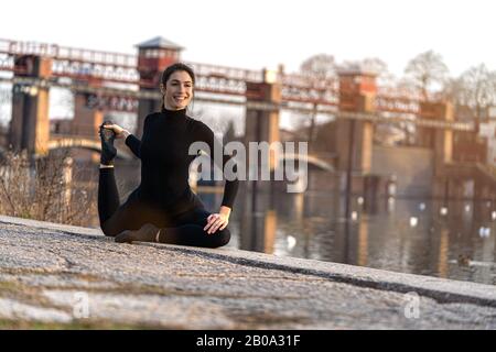 Portrait de la fille de sport faisant de l'exercice d'étirements de yoga sur le bord de la rivière Banque D'Images