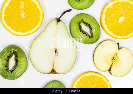gros fruits frais, tranchés, colorés, poire kiwi orange pomme sur fond blanc . Banque D'Images