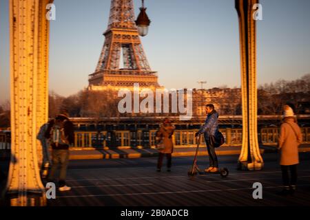 Un adulte prend un scooter près de la Tour Eiffel à Paris, France Banque D'Images