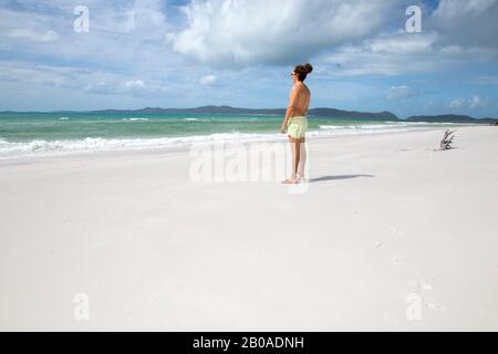 Homme aux cheveux bouclés, regardant la mer sur la plage de sable blanc de l'Australie Banque D'Images