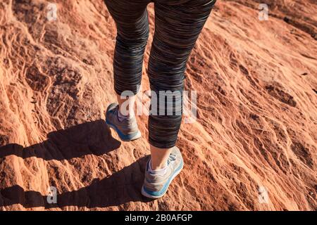 Chaussures de sport marchant le long d'une formation de roche dans le désert Banque D'Images
