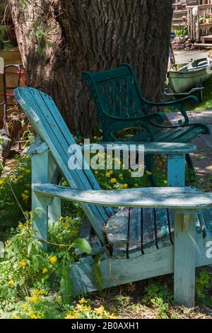 Ancienne chaise en bois peint turquoise Adirondack et banc de salon en métal vert dans la cour résidentielle en été. Banque D'Images