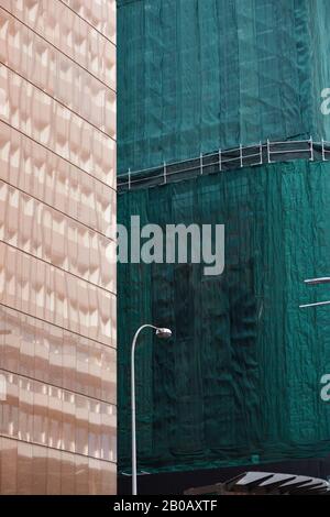 Démolition et réaménagement - contraste entre une façade de nouveau bâtiment en miroir et une réserve de 20 étages de tissu de construction vert à Sydney, en Australie Banque D'Images