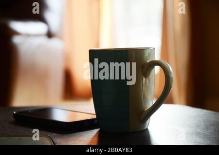 RÔTI DU DIMANCHE : une tasse de café fraîchement préparée repose sur une table de salon. Banque D'Images