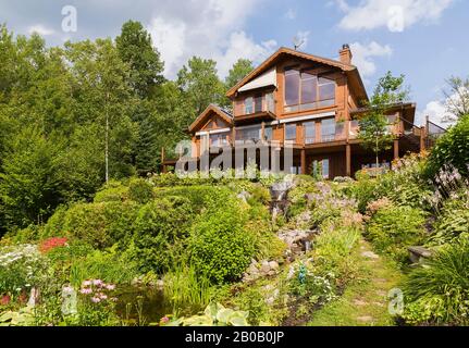 Arrière de la pièce colorée de brun doré sur pièce de pin blanc de l'est et maison en bois et jardin arrière incliné avec cascade cascade et ruisseau. Banque D'Images