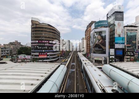 Un train sur le réseau de transport rapide en commun/métro léger élevé de Taipei quitte la gare Zhongxiao-Fuxing sur la ligne marron. Banque D'Images