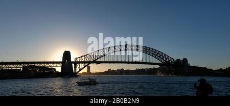 Panorama du Sydney Harbour Bridge au design Art déco, Dawes pointe en silhouette au crépuscule avec le coucher du soleil derrière le pylône sud, en Australie. Banque D'Images