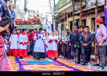 Santiago Atitlan, Guatemala - 19 avril 2019: La procession du vendredi Saint marche sur le tapis de sciure teints temporaire dans la ville du lac Atitlan. Banque D'Images