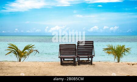 Belle photo de deux chaises d'fauteuil inclinable en bois vacants pour les touristes et les couples de lune de miel sur la plage pour de bons moments. Océan calme de couleur turquoise eau Banque D'Images