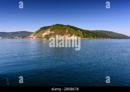 Ake Baikal près du village Port Baikal, Russie. Vue horizontale sur la haute rive, la forêt verte, les maisons, l'eau claire du lac en été Banque D'Images