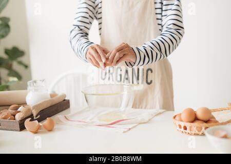 Les mains des hommes sont casser un oeuf dans un bol pour faire de la pâte sur le tableau blanc Banque D'Images