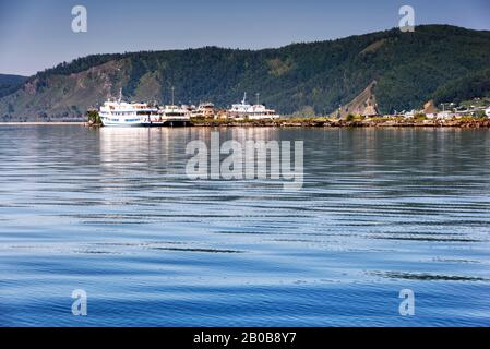 Lac Baikal près du village Port Baikal, Russie. Vue horizontale sur la haute rive, la forêt verte, les maisons, les navires, l'eau claire du lac en été Banque D'Images