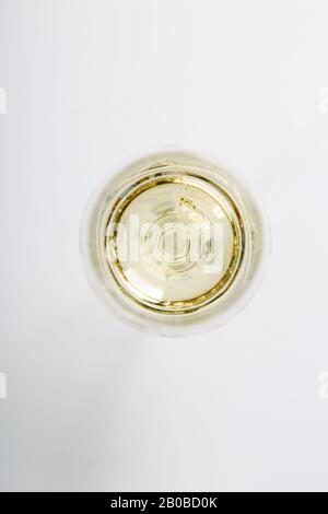 un verre de vin blanc se dresse sur un fond blanc. La vue du haut. Banque D'Images