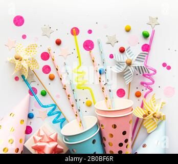 Chapeaux de fête d'anniversaire, pailles en papier, bonbons et confettis sur fond blanc Banque D'Images