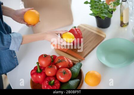 Les citruses dans les mains féminines sur une table avec des légumes. Banque D'Images